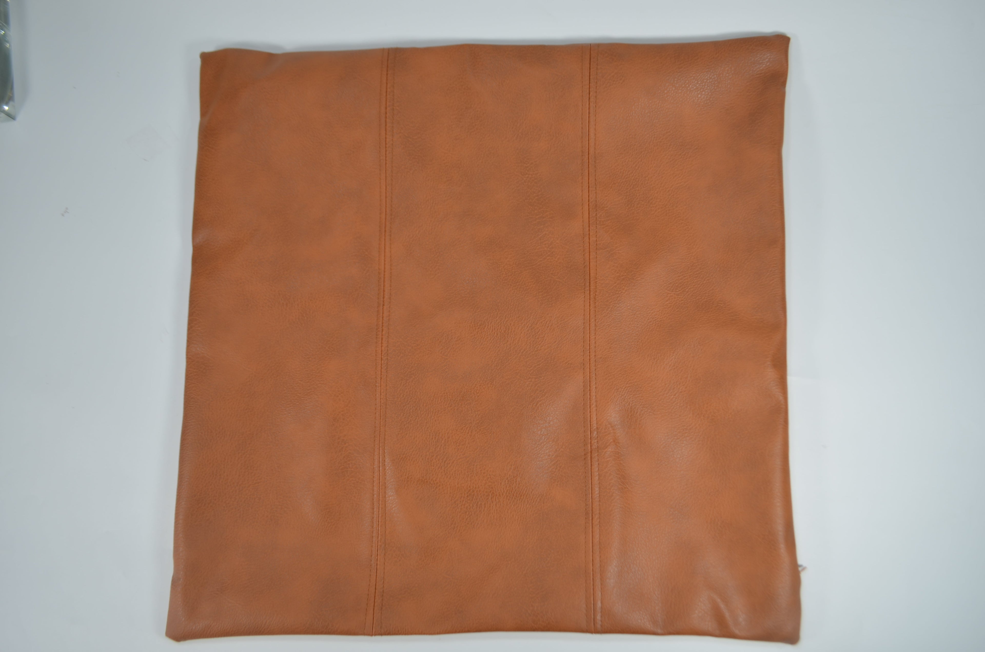 Brown faux leather cushion covers styled on a bed